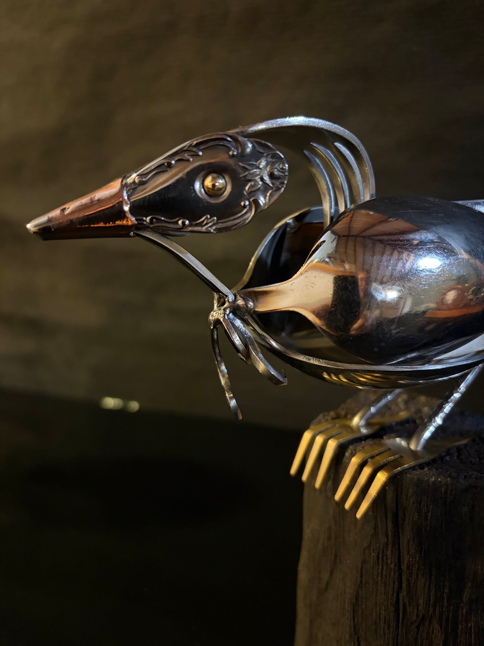 Metallic sculpture of a bird made from spoons and forks.