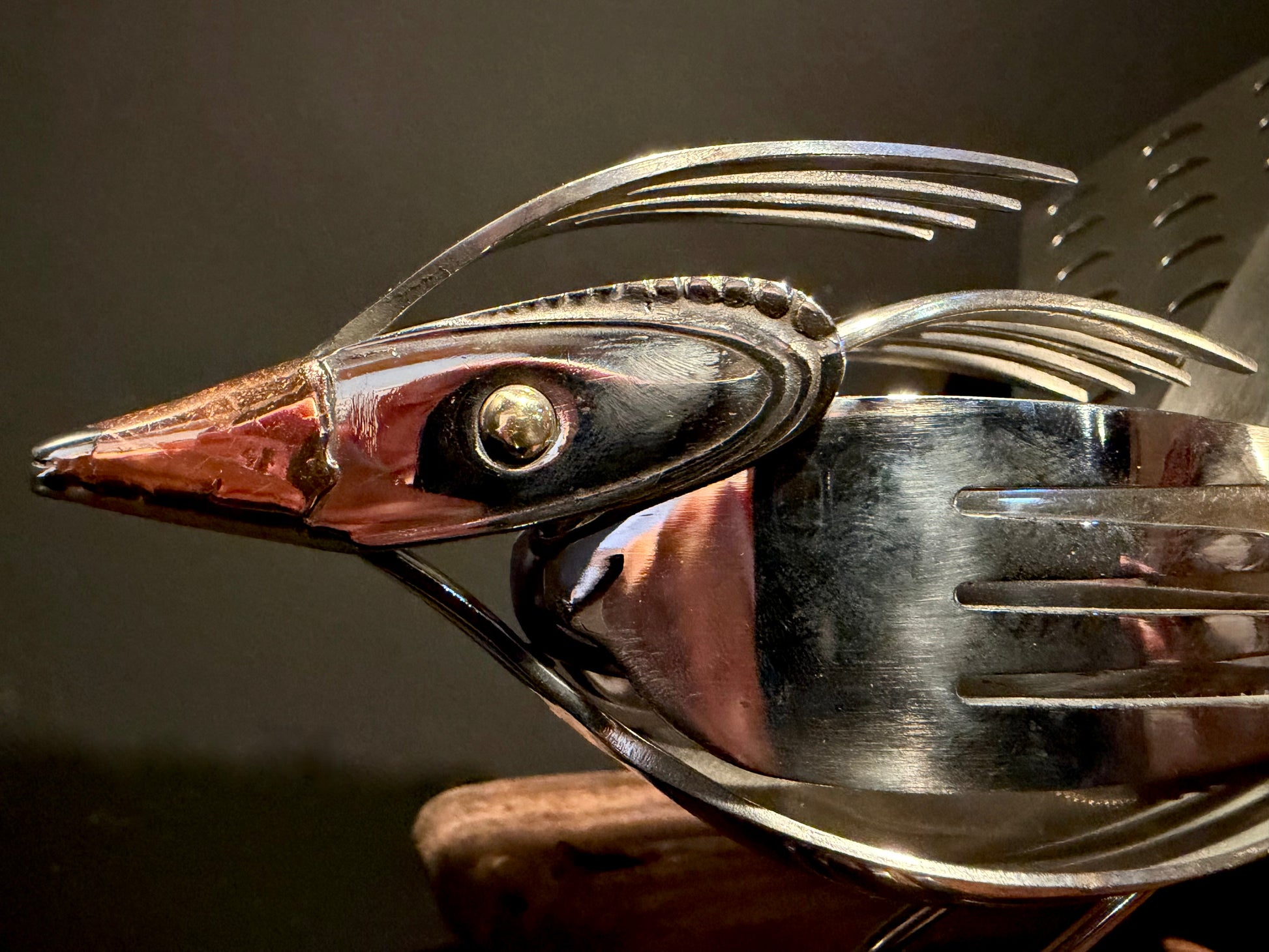 Metallic bird sculpture with detailed features and copper beak.