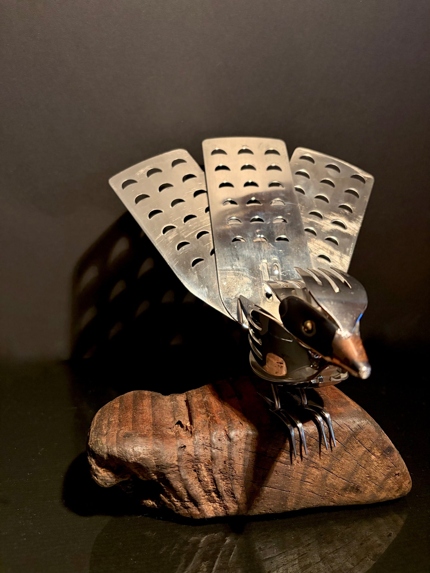 Metallic New Zealand Piwakawaka bird ornament on a wooden base. 