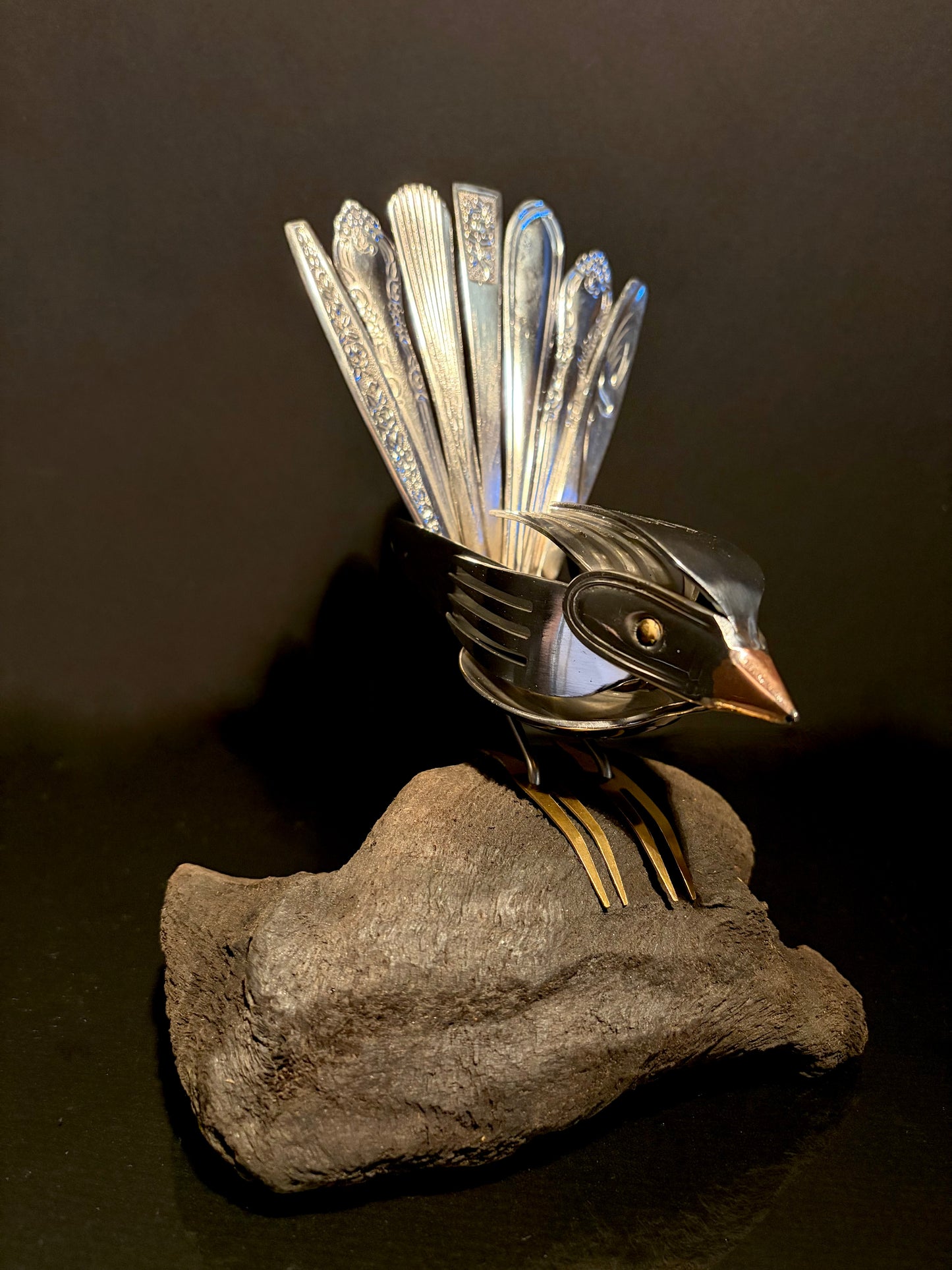 Cutlery sculpture sitting on wood.