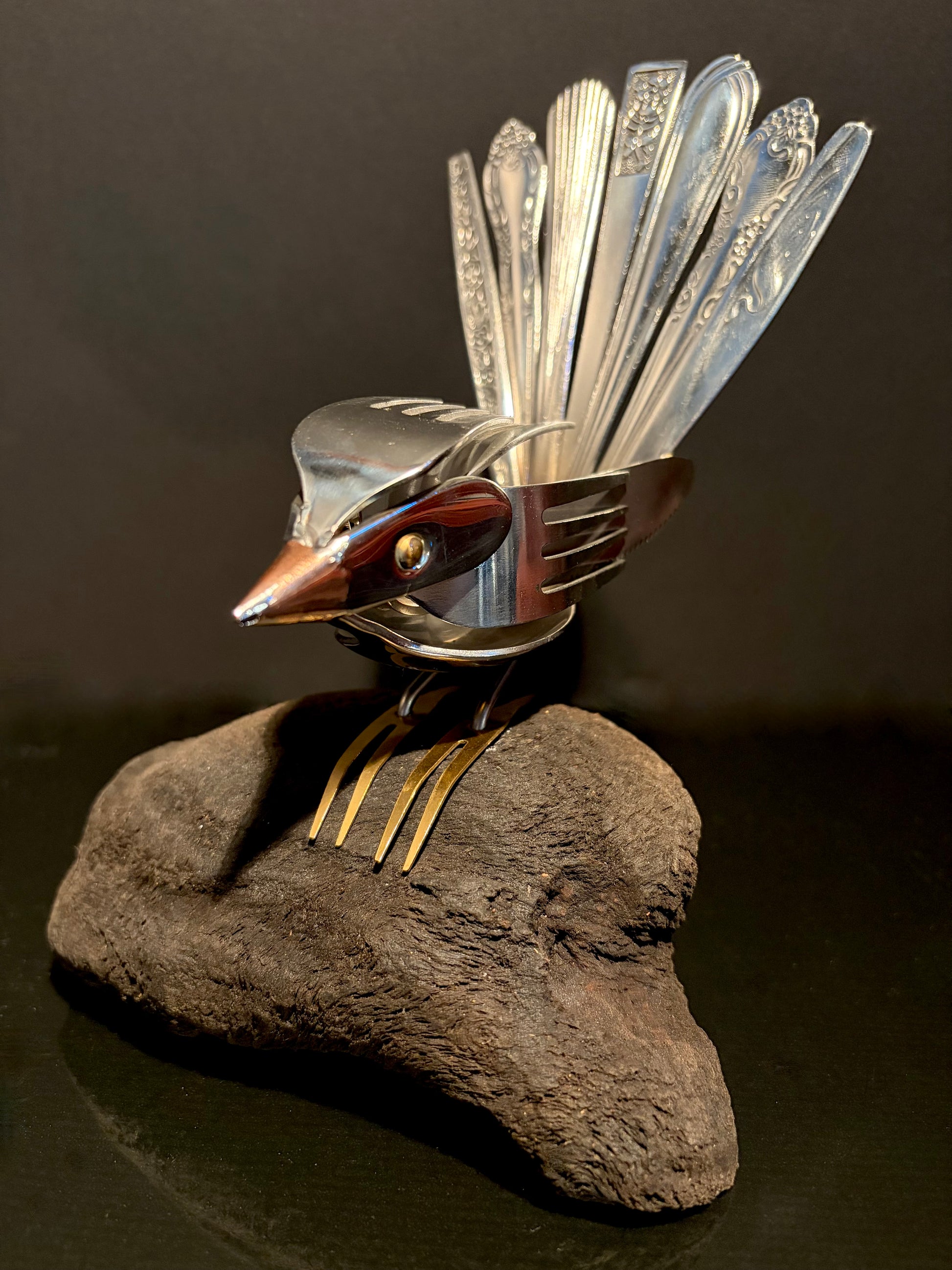 Bird sculpture made from cutlery on driftwood.