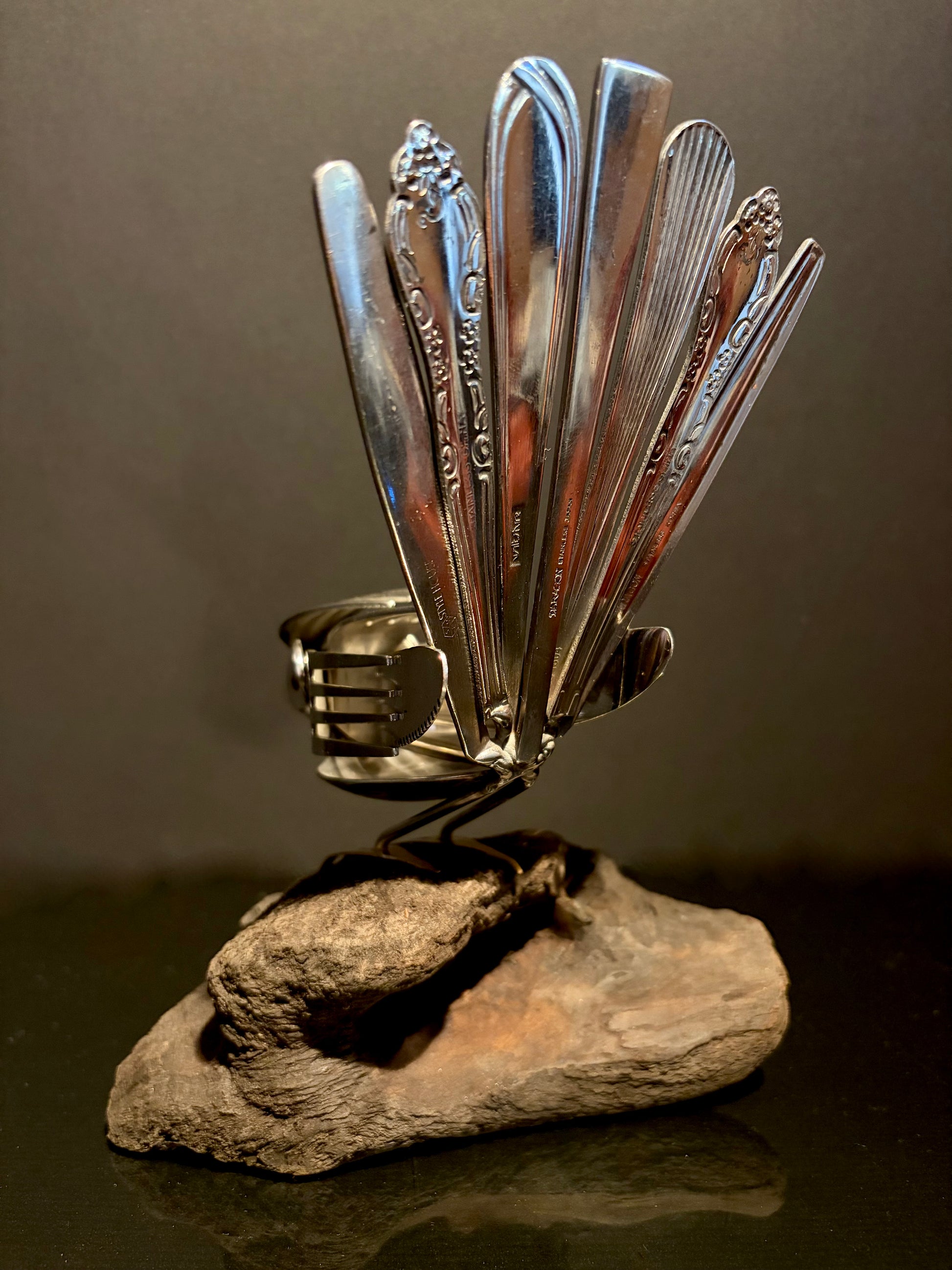 Decorative sculpture made from cutlery on a wood base.