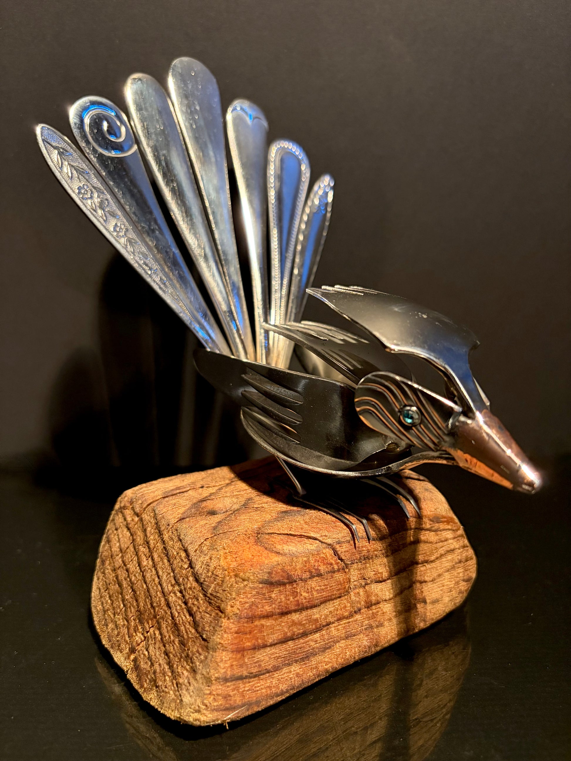 Metallic NZ bird sculpture on a wooden base.