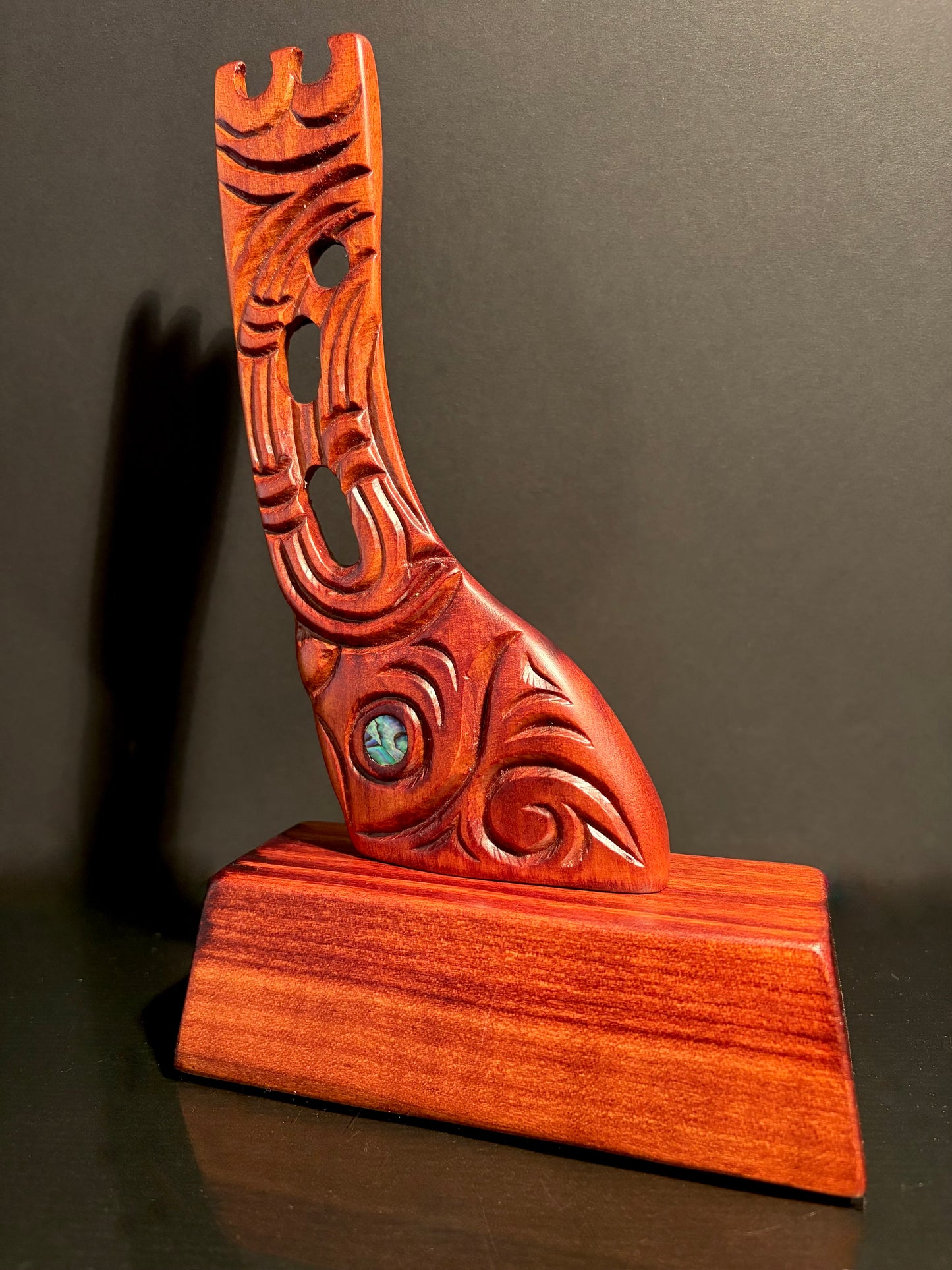 Wooden carving of a canoe stern mounted on a wood stand as a trophy or ornament.