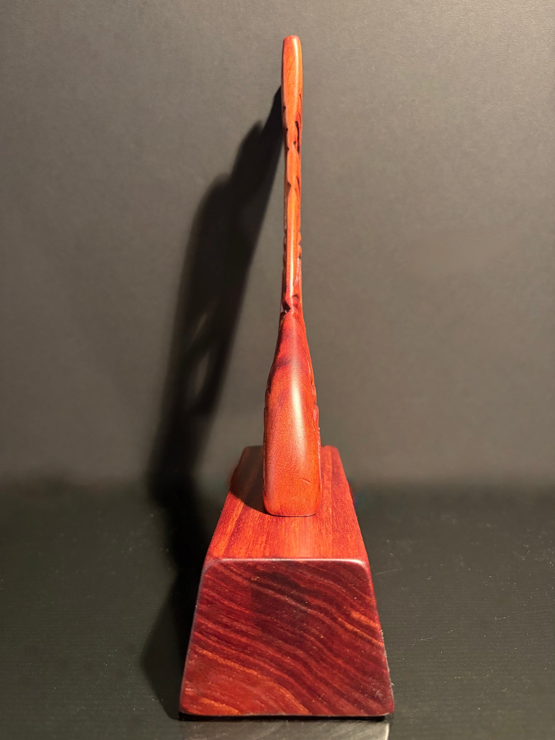 Side profile of Maori wooden canoe stern mounted on a wood stand as a trophy or ornament. 