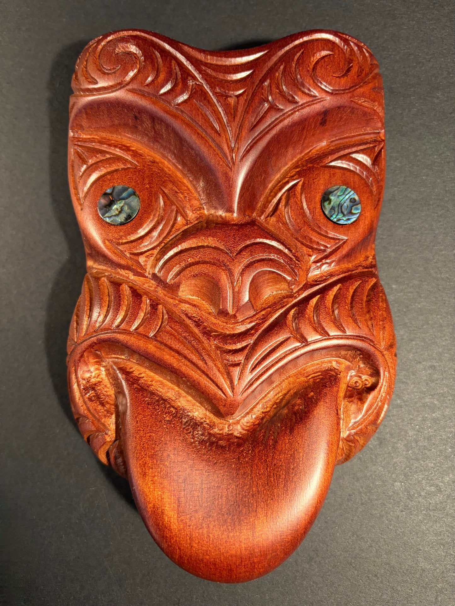 Wooden mask with intricate carvings on a grey background