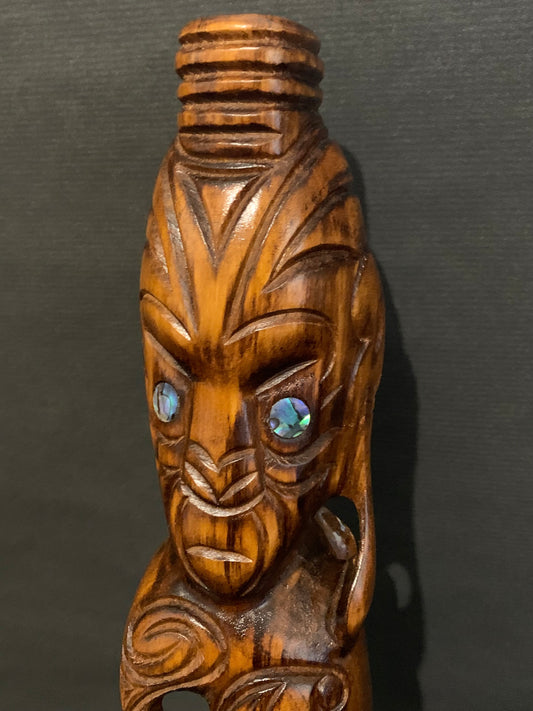 Showing carved earring of Maori warrior New Zealand Maori teko teko carved by Wood Masters Silver Fern Gallery