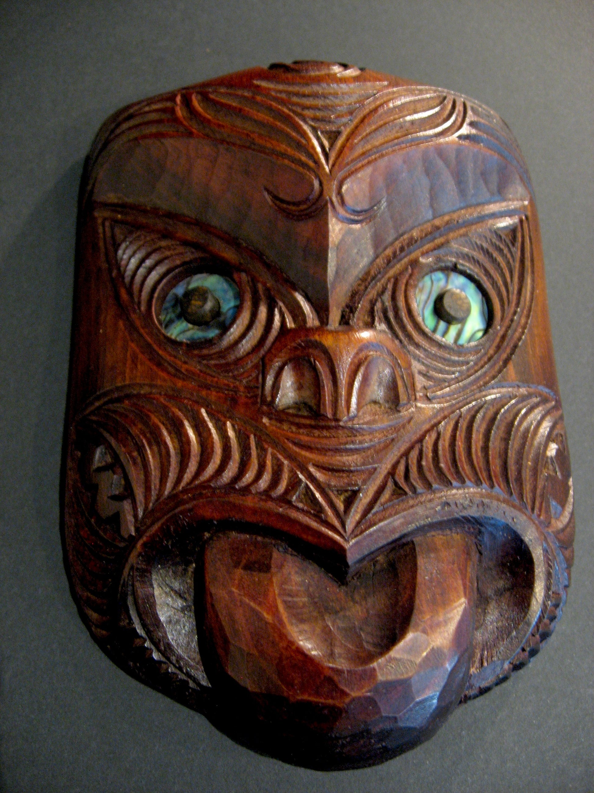 Wooden mask with intricate carvings on a gray background