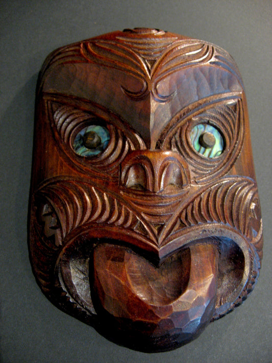 Wooden mask with intricate carvings on a gray background