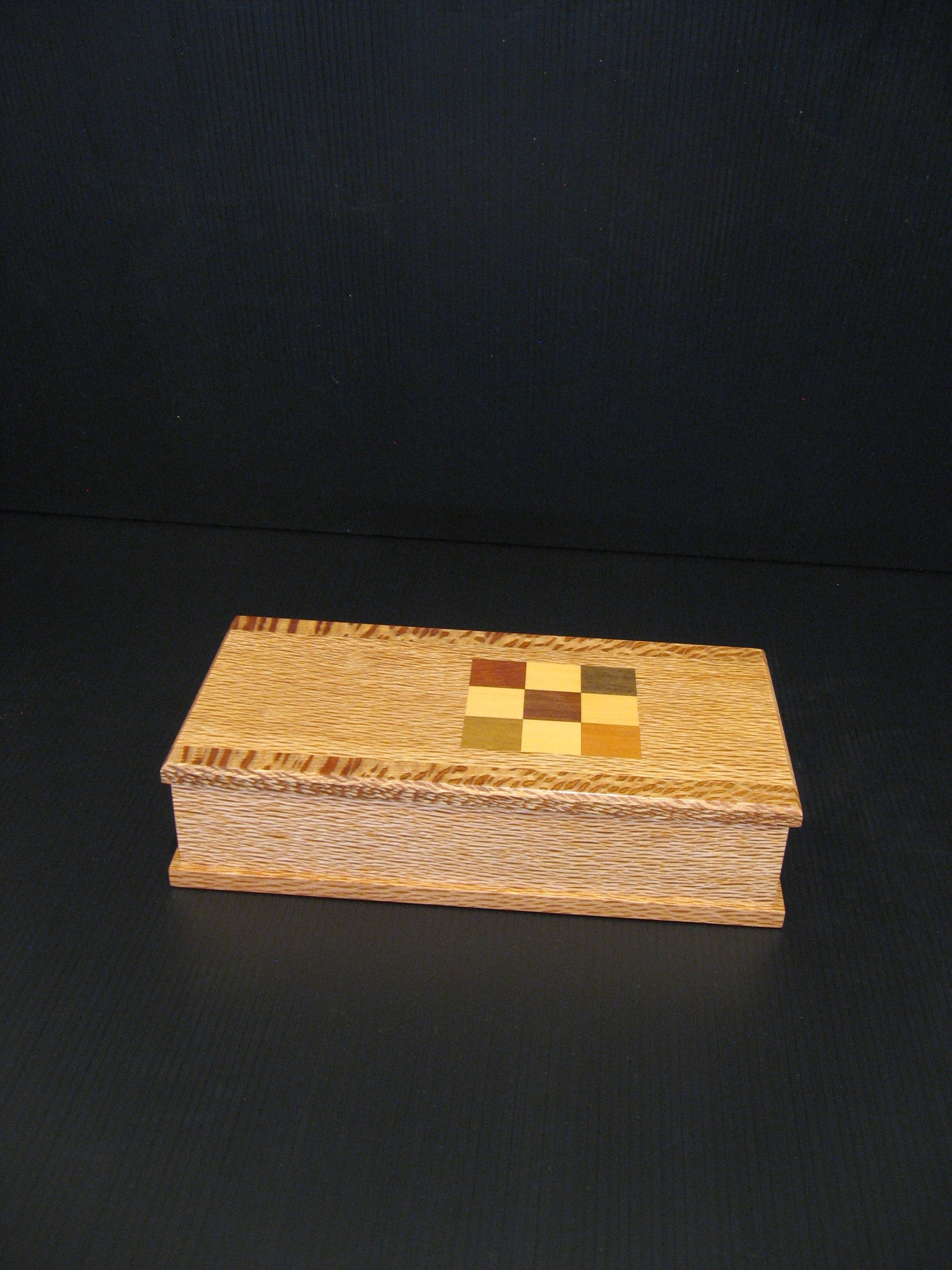 A rectangular wooden keepsake box with a checkerboard inlay on the lid.