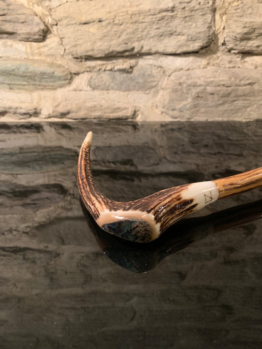 A curved deer antler walking stick handle with paua shell inlay and NZ engraved on it 