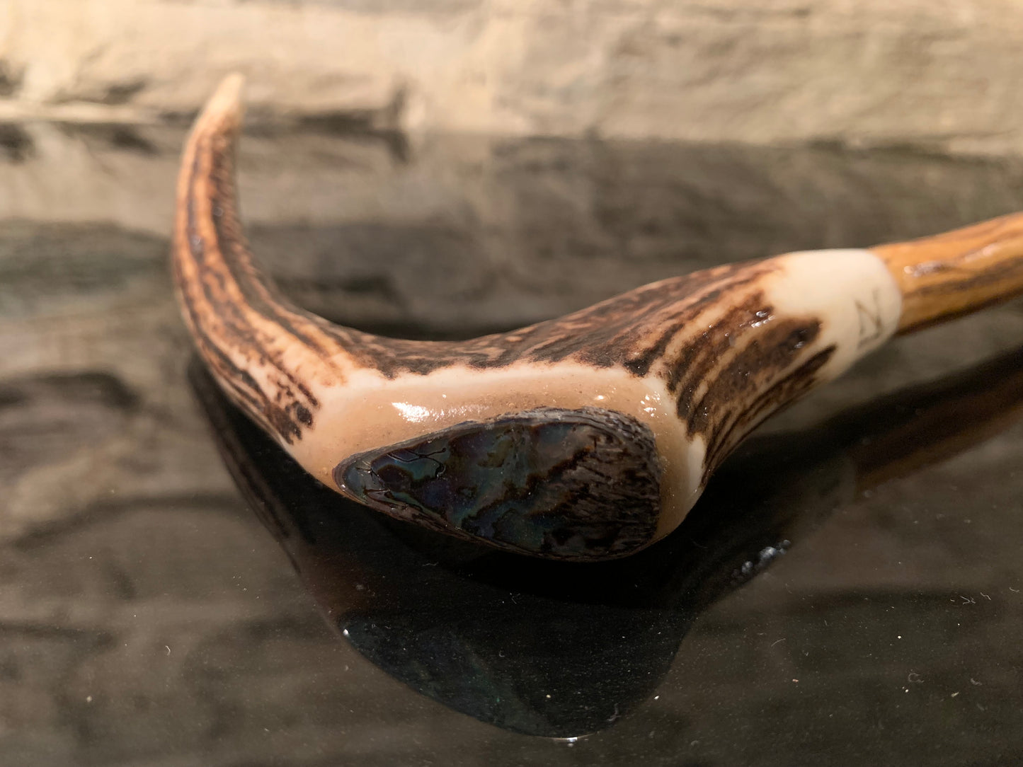 A curved antler walking stick handle with NZ paua shell inlay