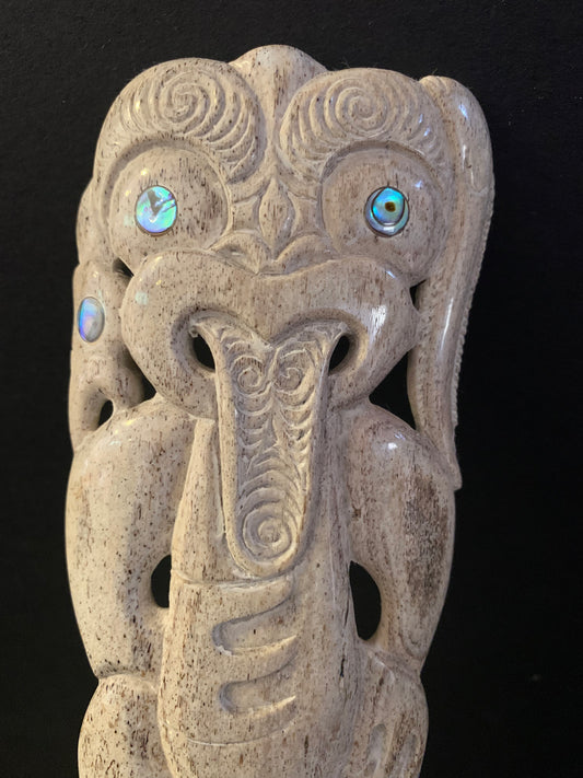 close up detail of a hand-carved whale bone comb with intricate designs and decorative elements,  against a black background.