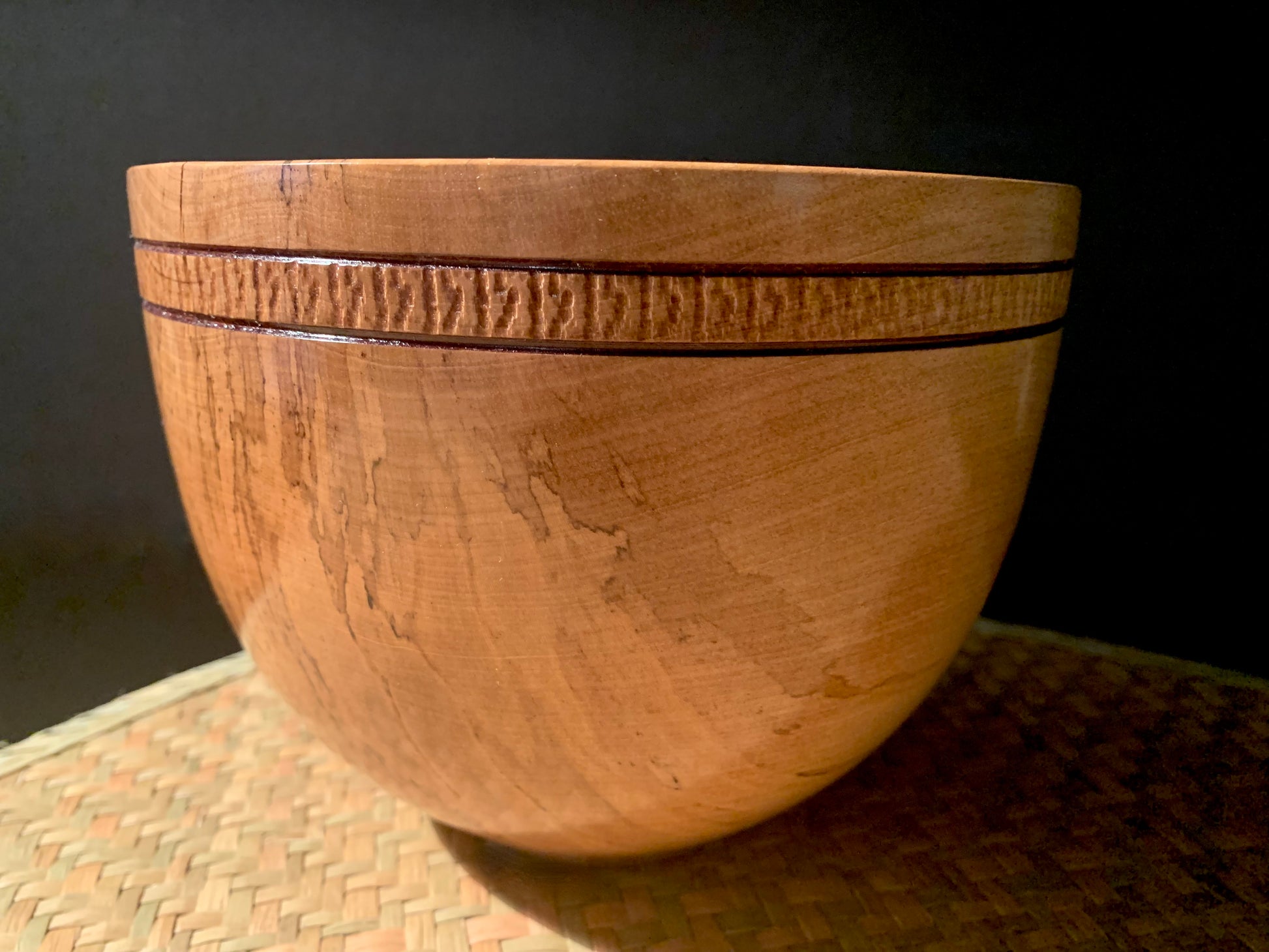 Feature wooden bowl with patter on souter urface under the rim.