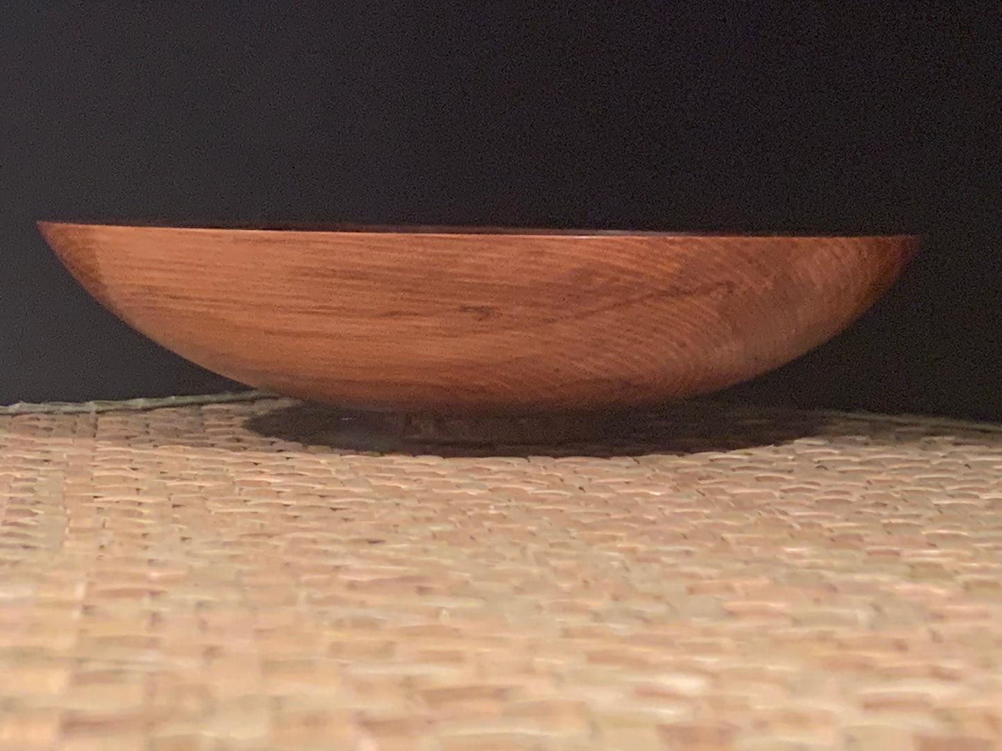 Wooden bowl on a textured surface with a black background.
