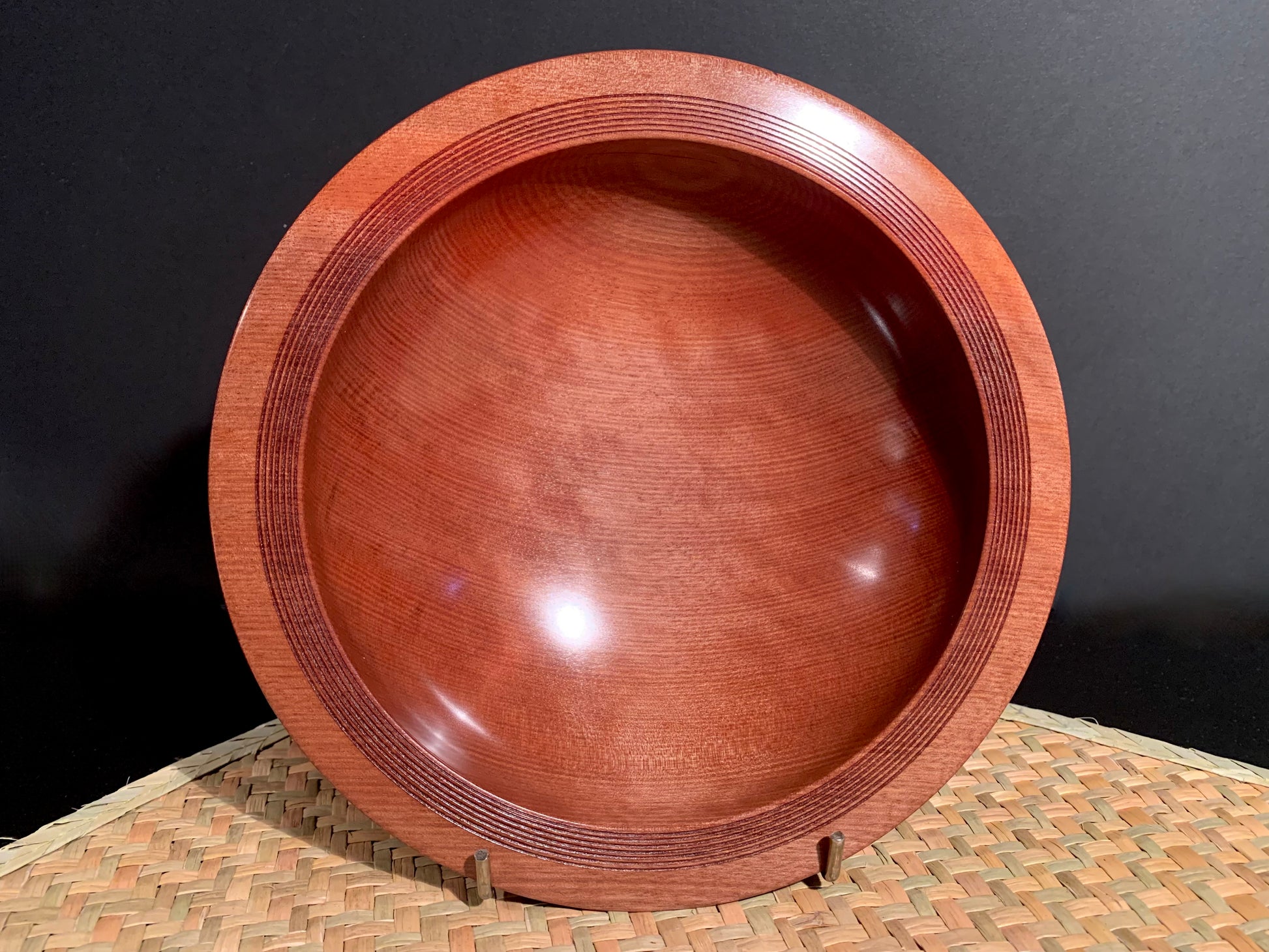 Wooden bowl with a wide rim and mulitple groove detail on the rim.