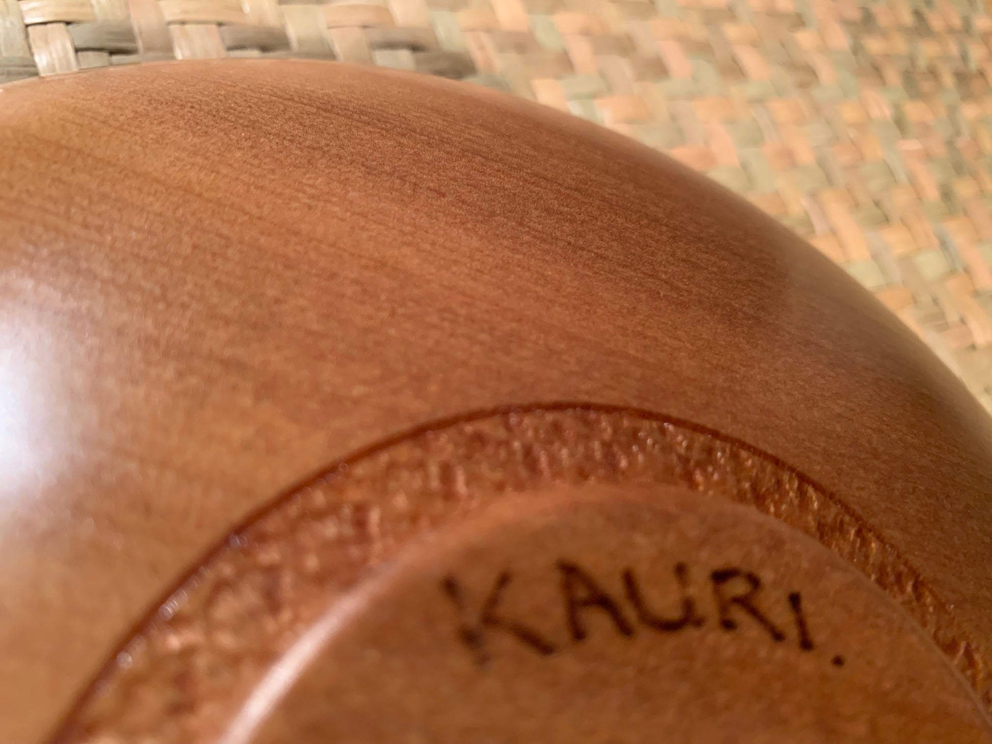 Close-up of a wooden bowl base with 'Kauri' engraved on it.
