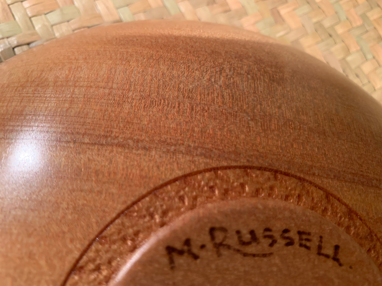 Close-up of a wooden bowl base with artists signature engraved on it.