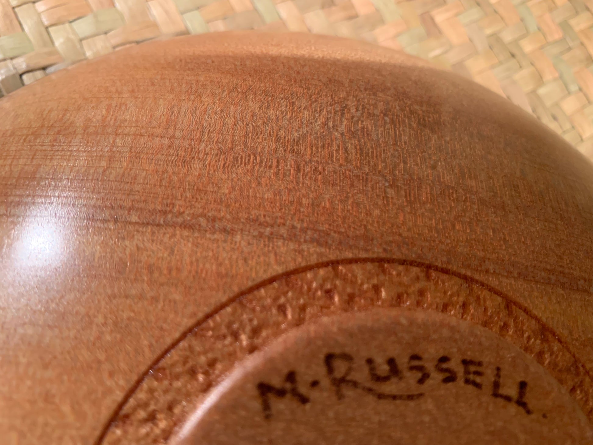 Close-up of a wooden bowl base with artists signature engraved on it.