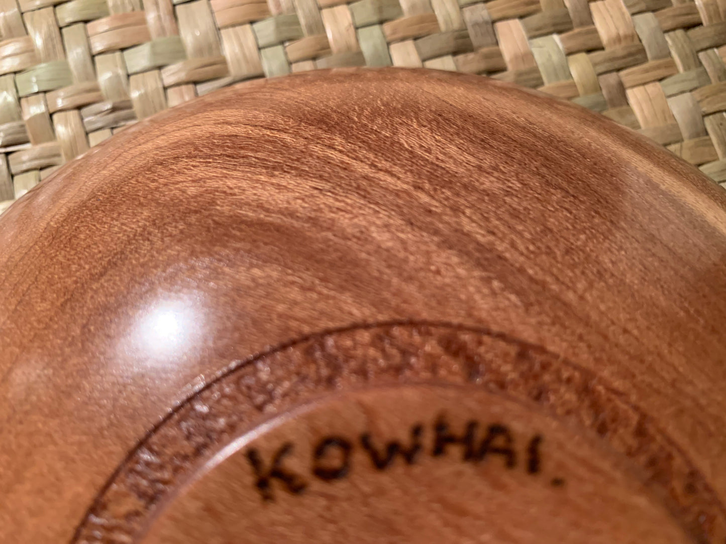 Close-up of underneath a wooden bowl with 'Kowhai' engraving.