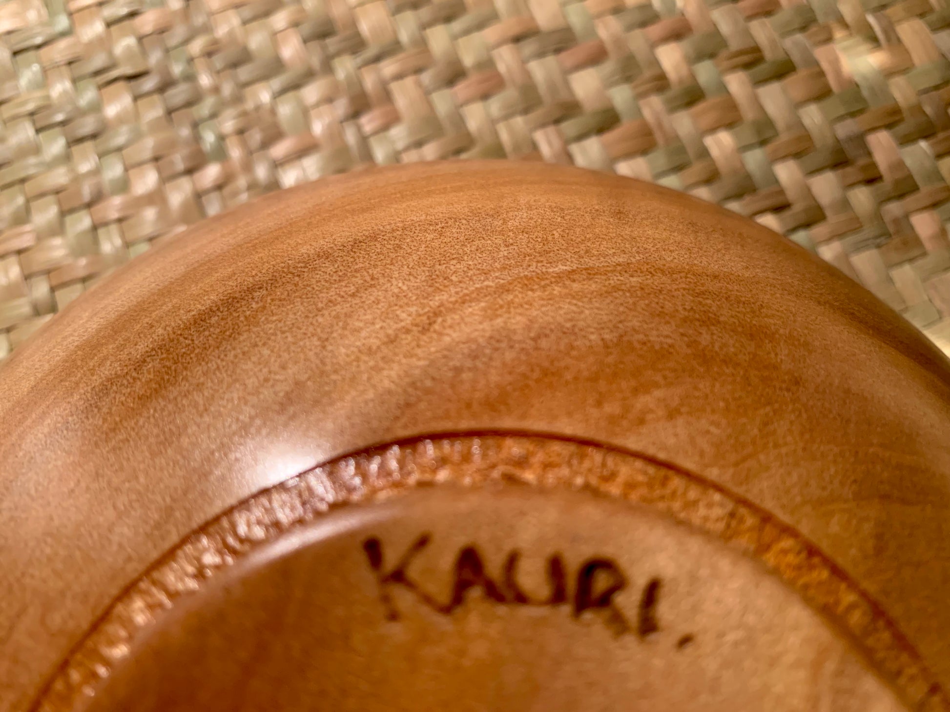 Close-up of a wooden bowl base with 'Kauri' branding.