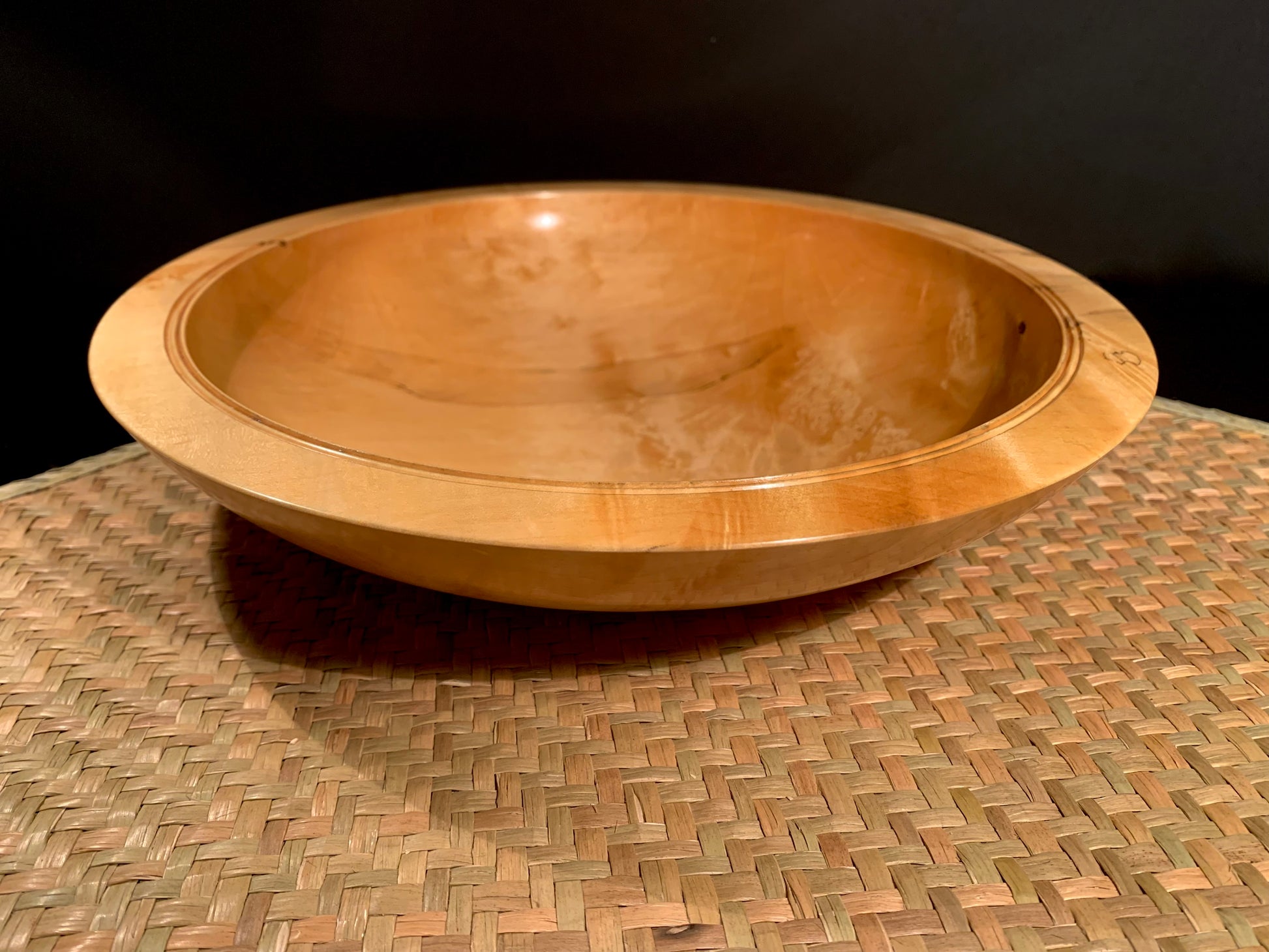 Wooden bowl on a woven surface with a dark background