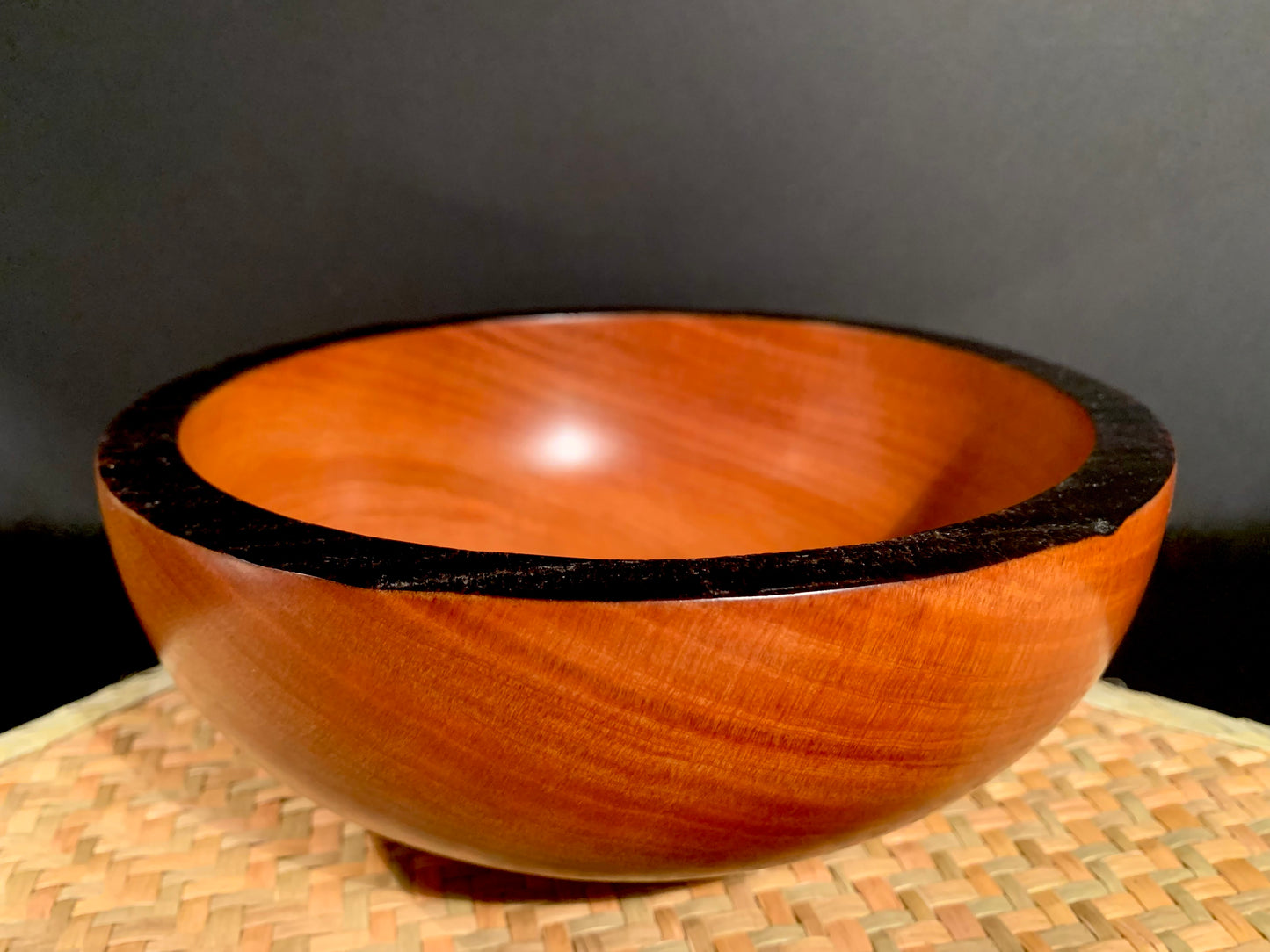 Wooden handcrafted bowl with black rim .