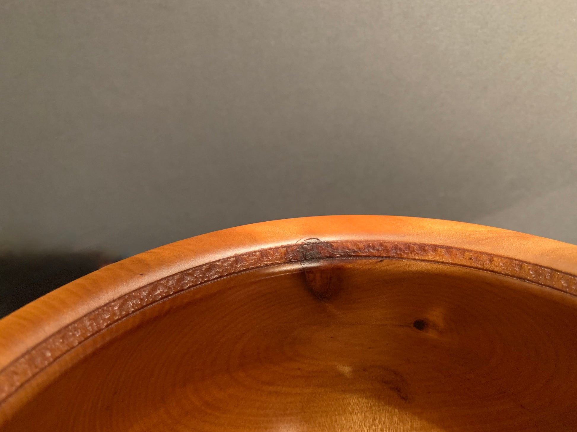 Wooden bowl rim with intricate handstamped design.
