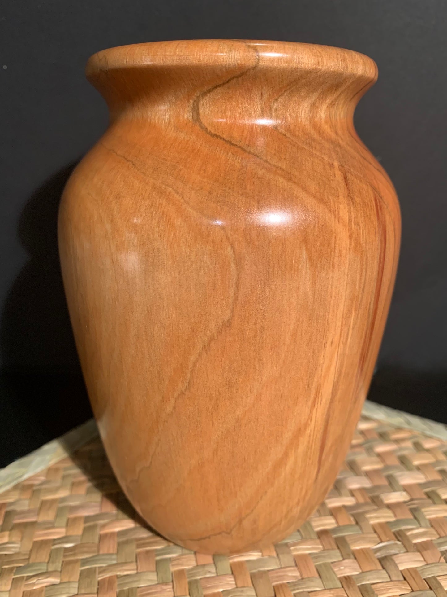 Wooden vase of a classical urn shape with grain highlighting the curves of the vase.