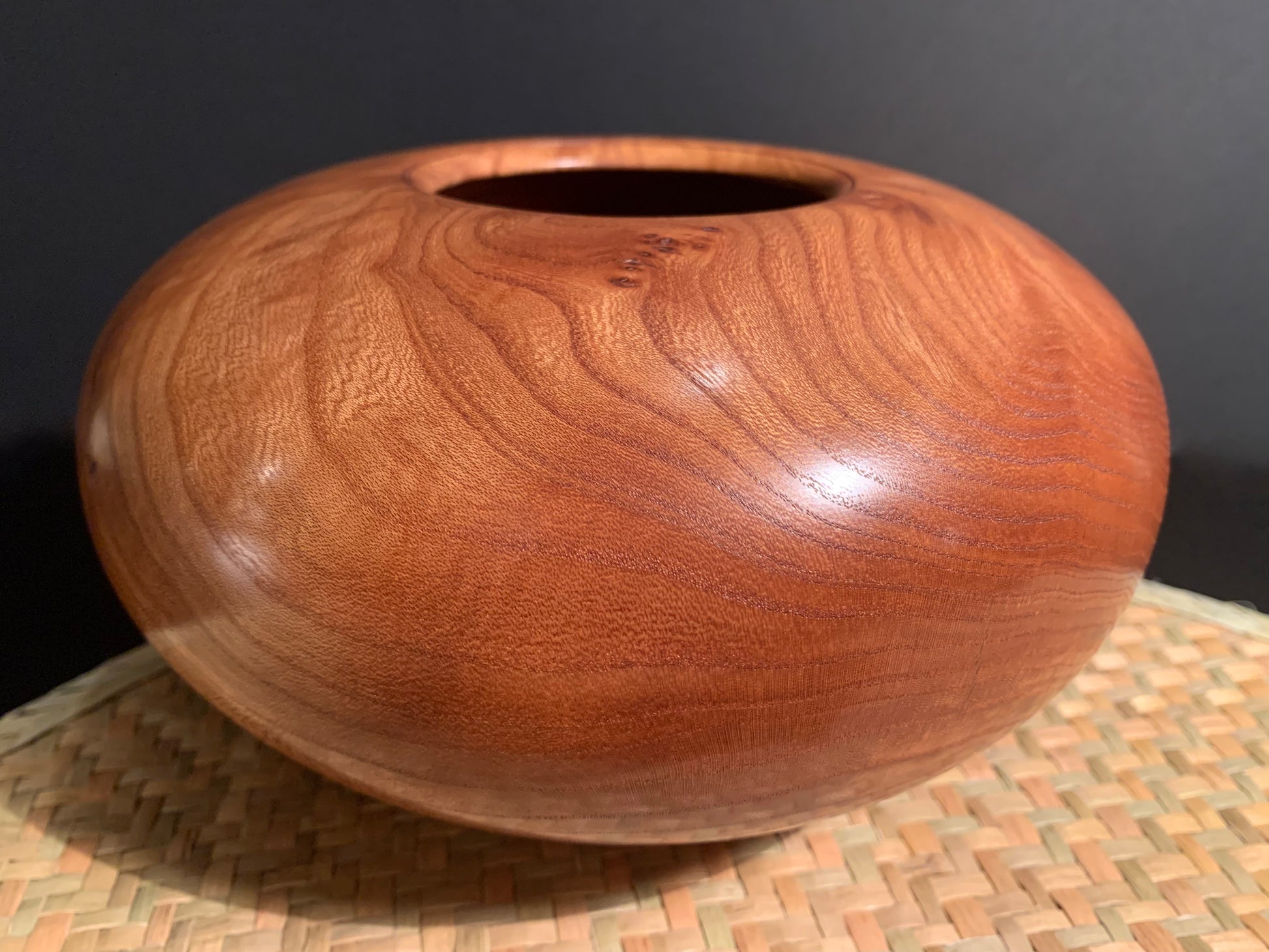Wooden urn with smooth surface showing patterned woodgrain. 