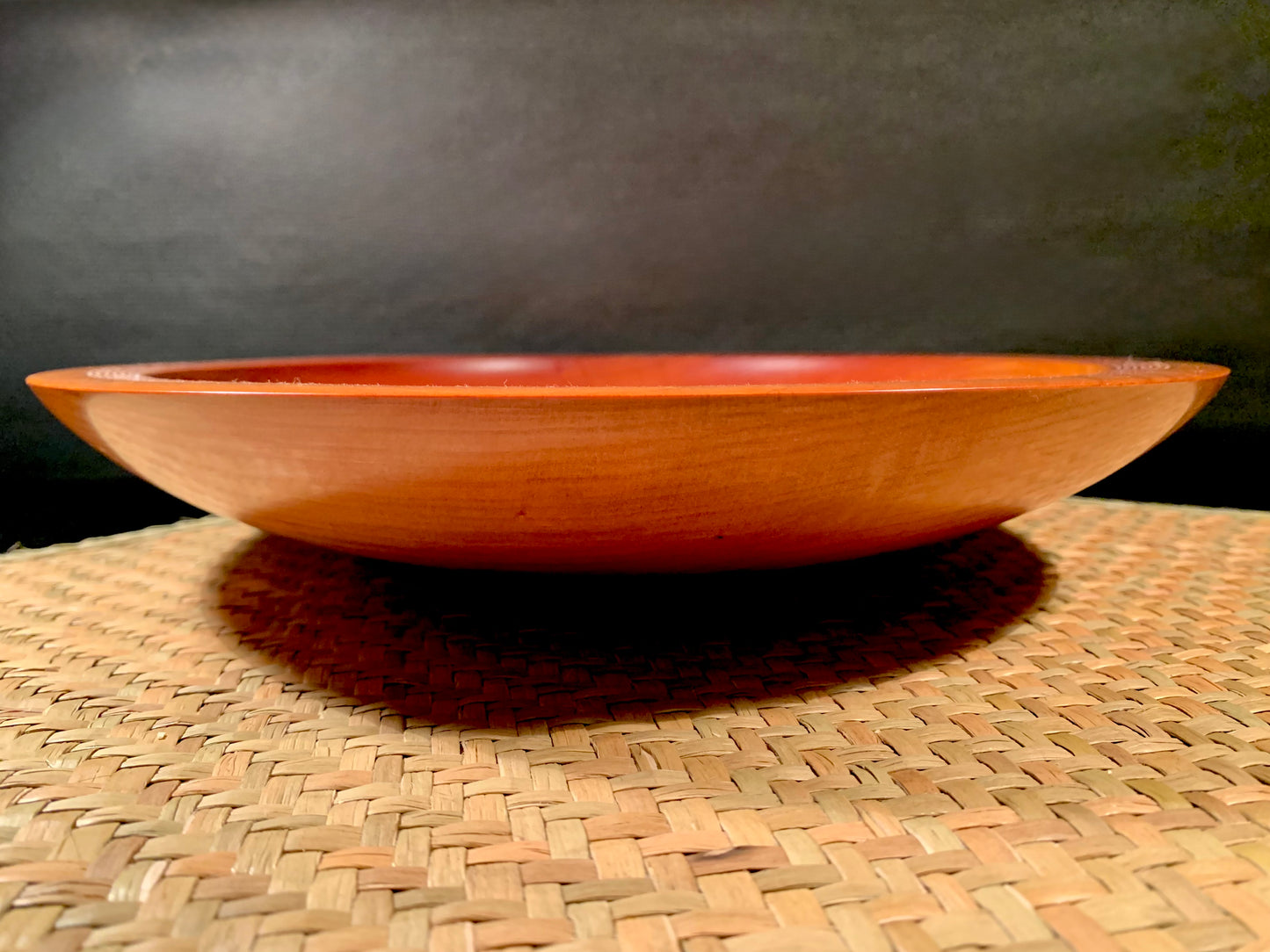 Woodturned handcrafted bowl on a woven surface.