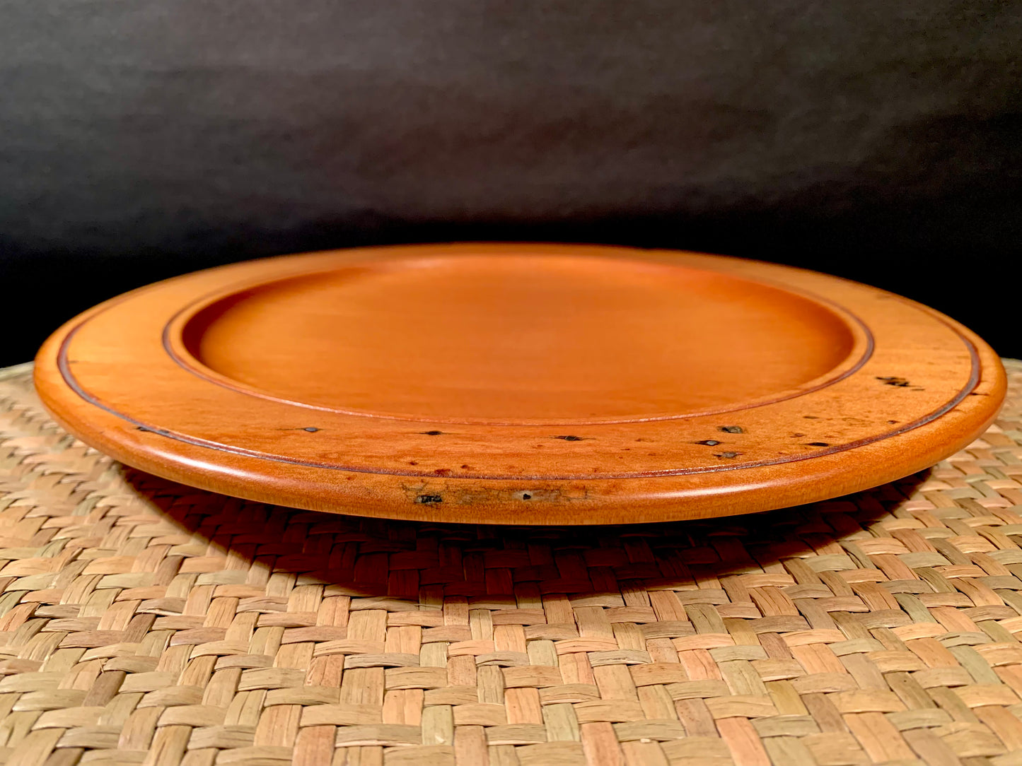 Wooden plate on a woven mat with a dark background.