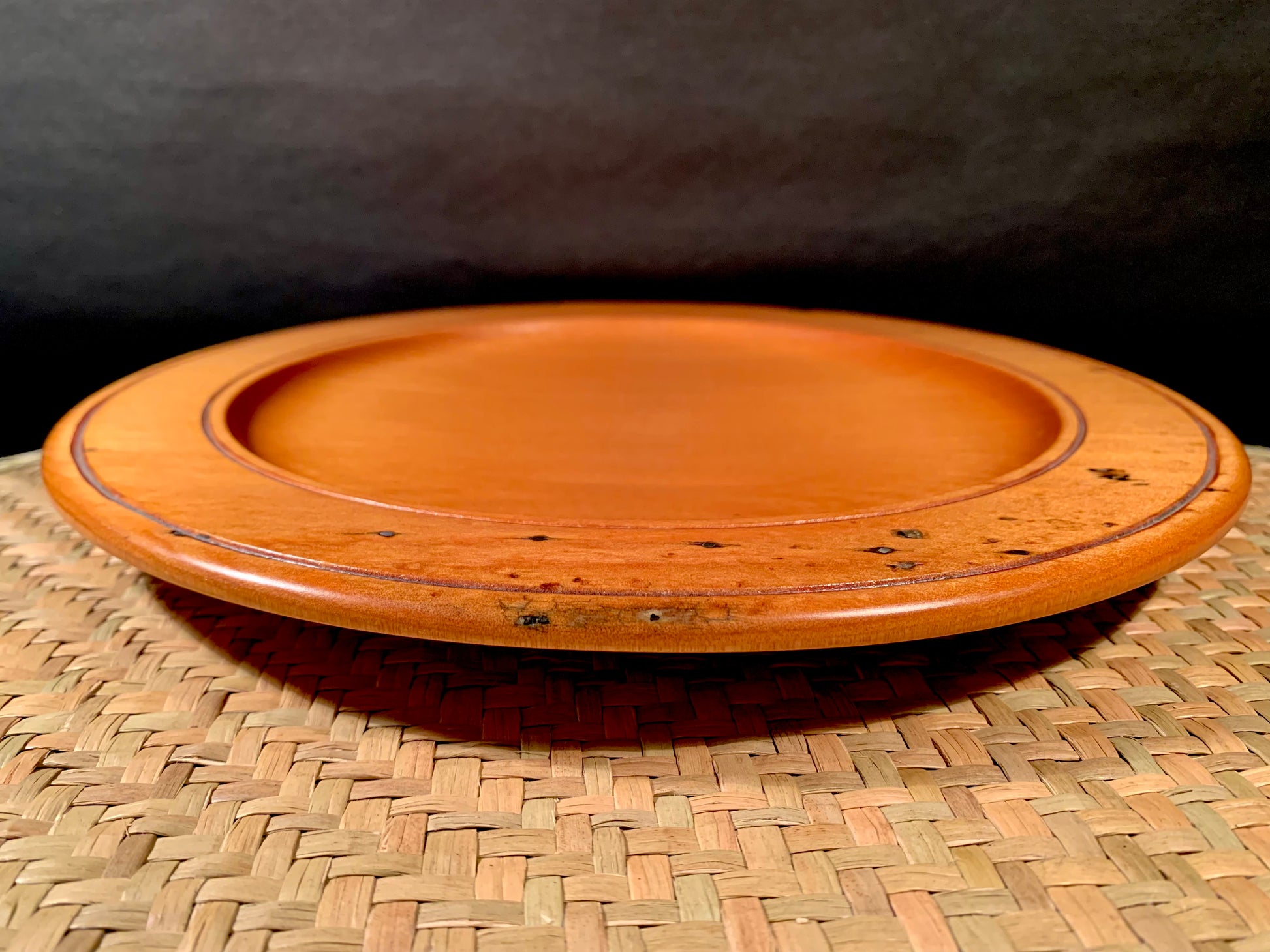 Wooden plate on a woven mat with a dark background.