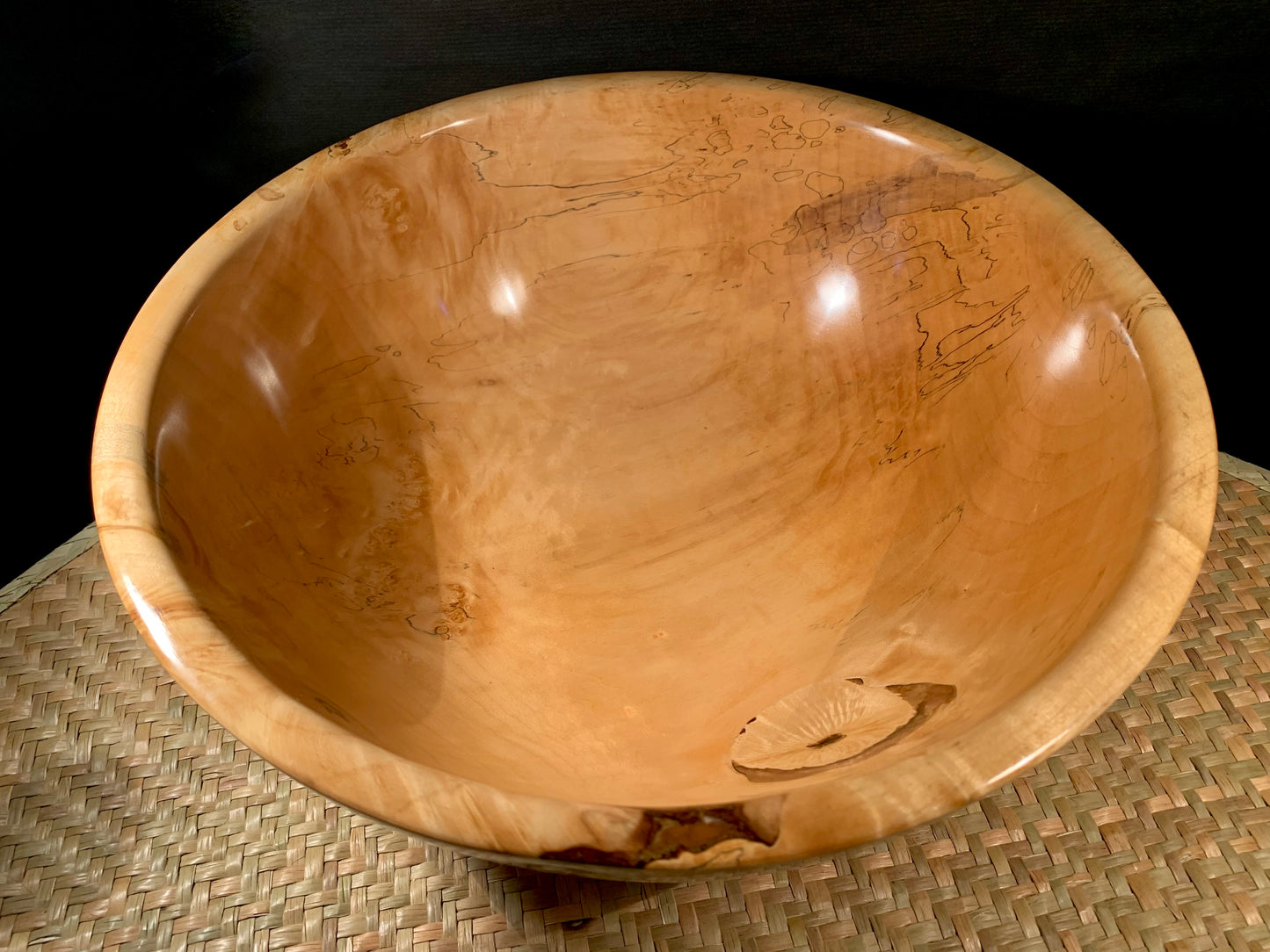 Wooden bowl on a woven mat.