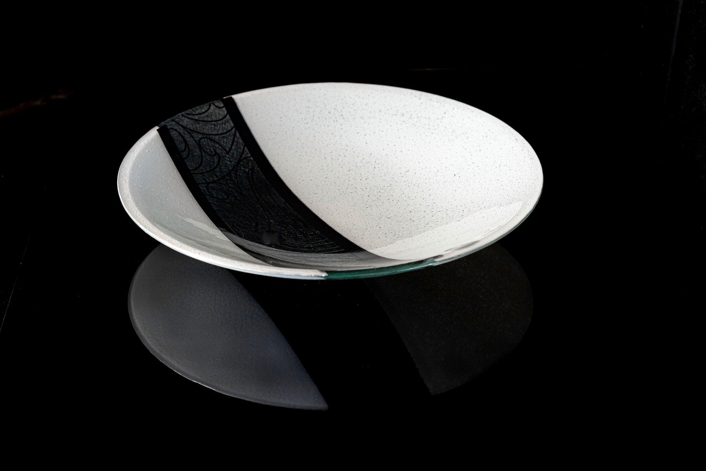 Angled view of Fused Glass Bowl by Maori Boy - Rongo Design (white and black) Silver Fern Gallery